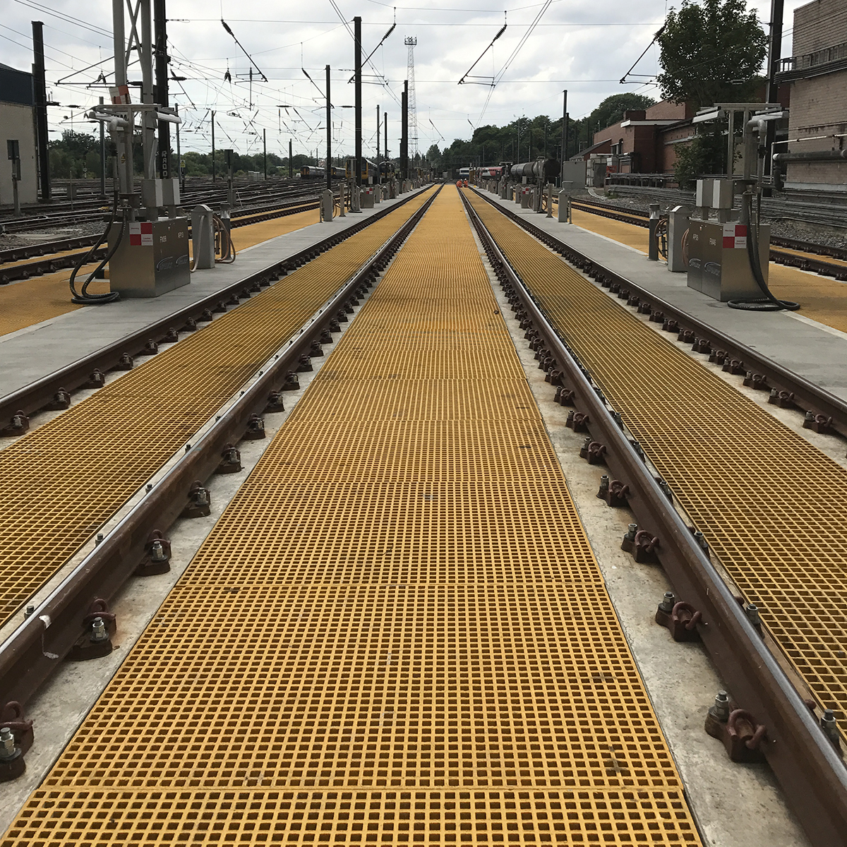 Yellow QuartzGrip Standard GRP Open Mesh Grating installed between railway tracks at a NWR depot