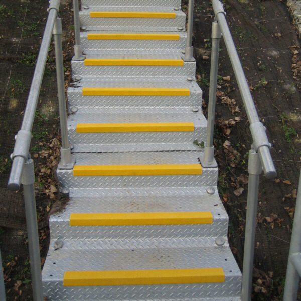 Yellow anti-lip stair nosing installed on metal checker plate steps