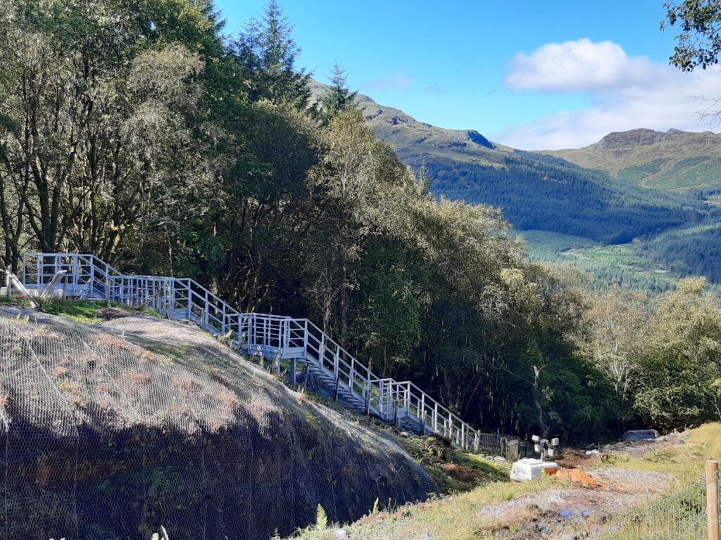 A long GRP embankment staircase winding down to a track in Scottish Highlands