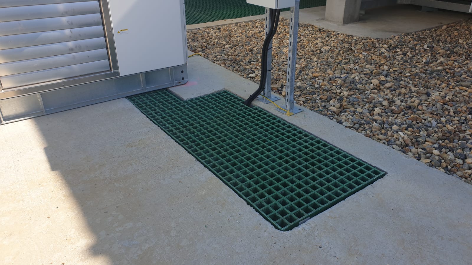 Green QuartzGrip GRP Open Mesh Grating used to cover a rectangular trench in a concrete foot path at a water treatment works