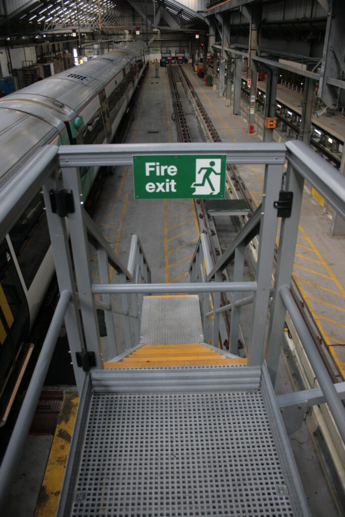 Self closing safety gate at the top of stairs leading down from a high level maintenance platform
