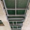 Green GRP grating Service riser set into the floor of a high-rise building . Photographed from the floor below to show the GRP profiles used to support the riser floor.