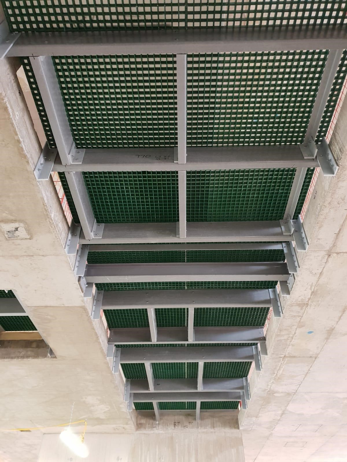 Green GRP grating RiserDeck Service riser set into the floor of a high-rise building . Photographed from the floor below to show the GRP profiles used to support the riser floor.
