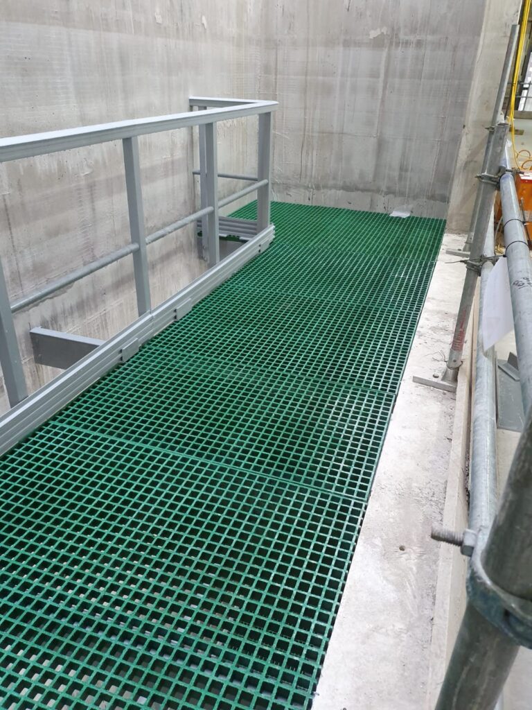 A Riser Floor in green GRP Grating with a handrail protecting an open void