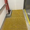 Yellow GRP grating Service riser set into the floor of a high-rise building