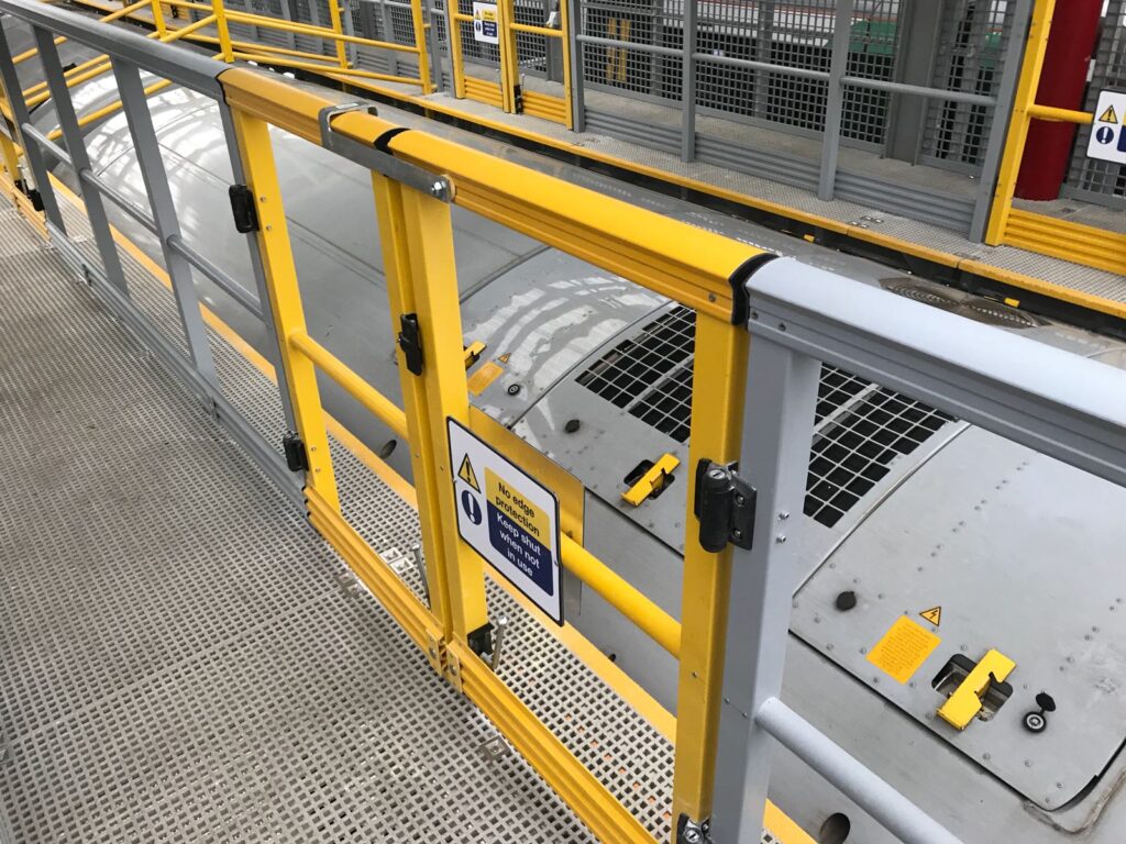 Self closing gate in the handrail of a high level platform