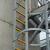 Yellow GRP anti-slip Ladder rung covers installed on a steel cat ladder climbng the side of a storage tank