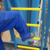 Close-up of yellow GRP ladder rung covers with a workman stepping onto the first rung
