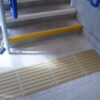 Corduroy tactile flooring at the foot of a staircase to warn those with visual impairment of the trip hazard