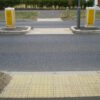 Inline blister tactile flooring at a road crossing to warn those with visual impairment of the potential hazard