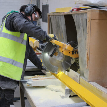 Step on Safety team member operating a large chop saw, cutting GRP stair nosing to meet a client's requirements