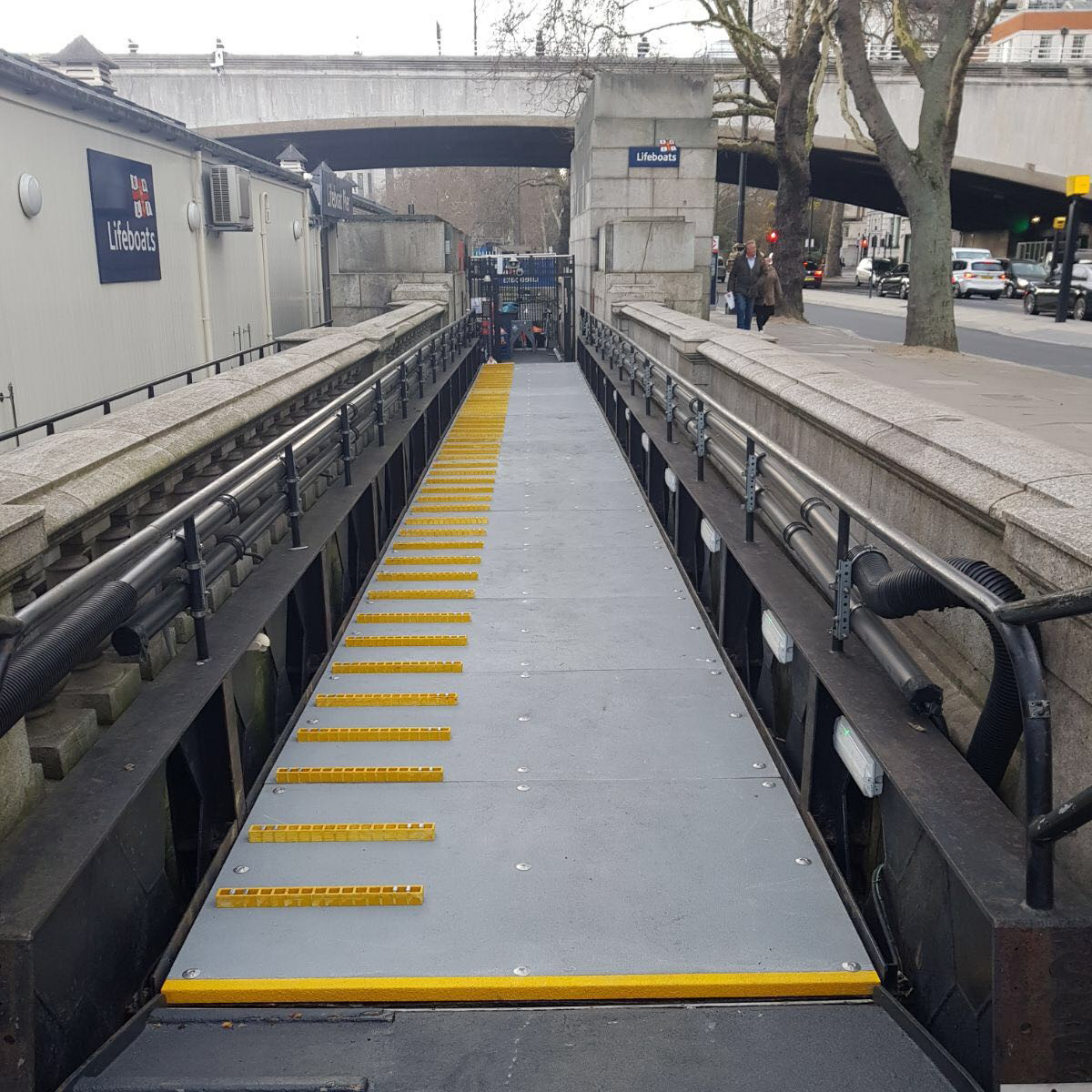A pedestrian walkway from the shore to a jetty providing crew access to an RNLI lifeboat. Ramp is surfaced with QuartzGrip Anti-slip Flooring Sheets in grey with narrow strips of Open mesh to create extra traction if required