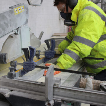 Step on Safety team member operating a large industrial saw, trimming GRP stair nosing to meet a client's requirements