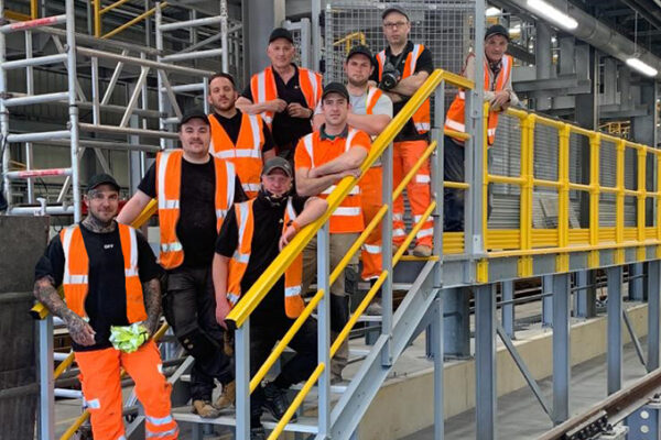 A shot of the Step on Safety team in orange hi-vis standing on the GRP steps at the end of the maintenance platform they have just completed