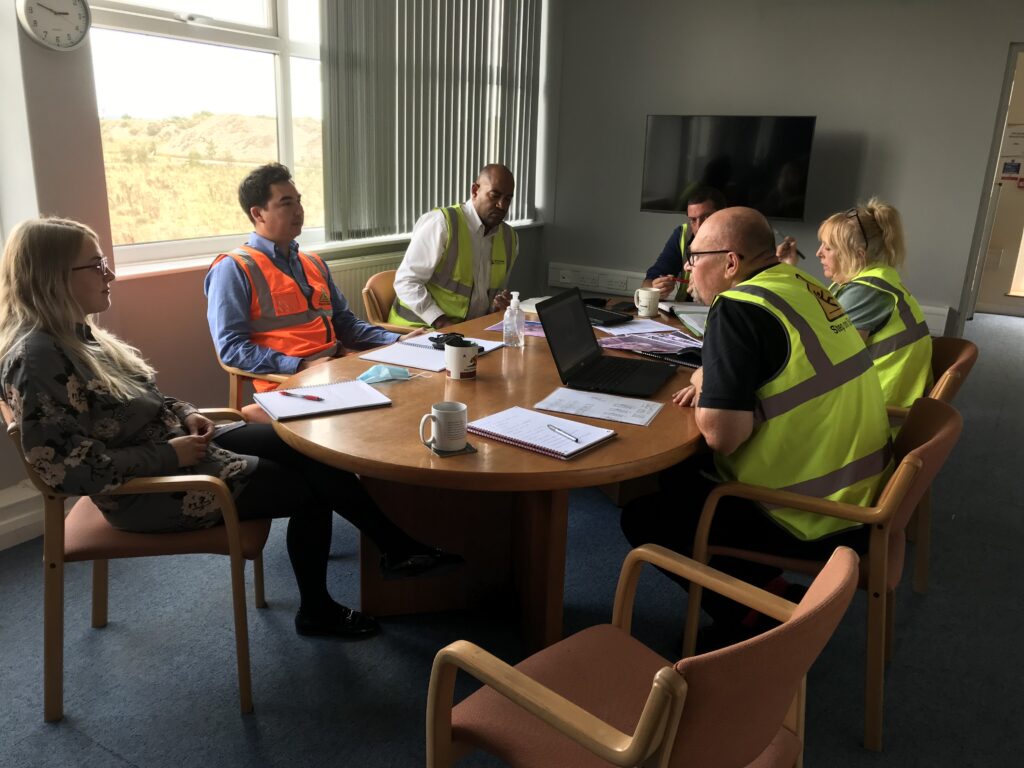 A group of people having a meeting a large table in an office boardroom