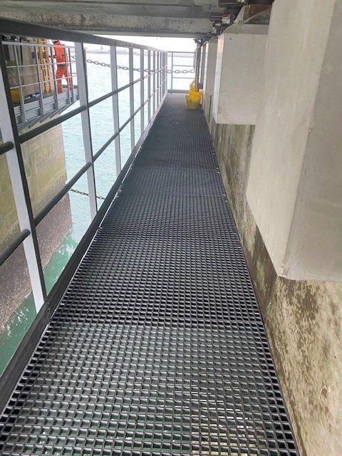 Photo taken on a GRP platform below a concrete pier at Dover showing the grey GRP grating and the handrail