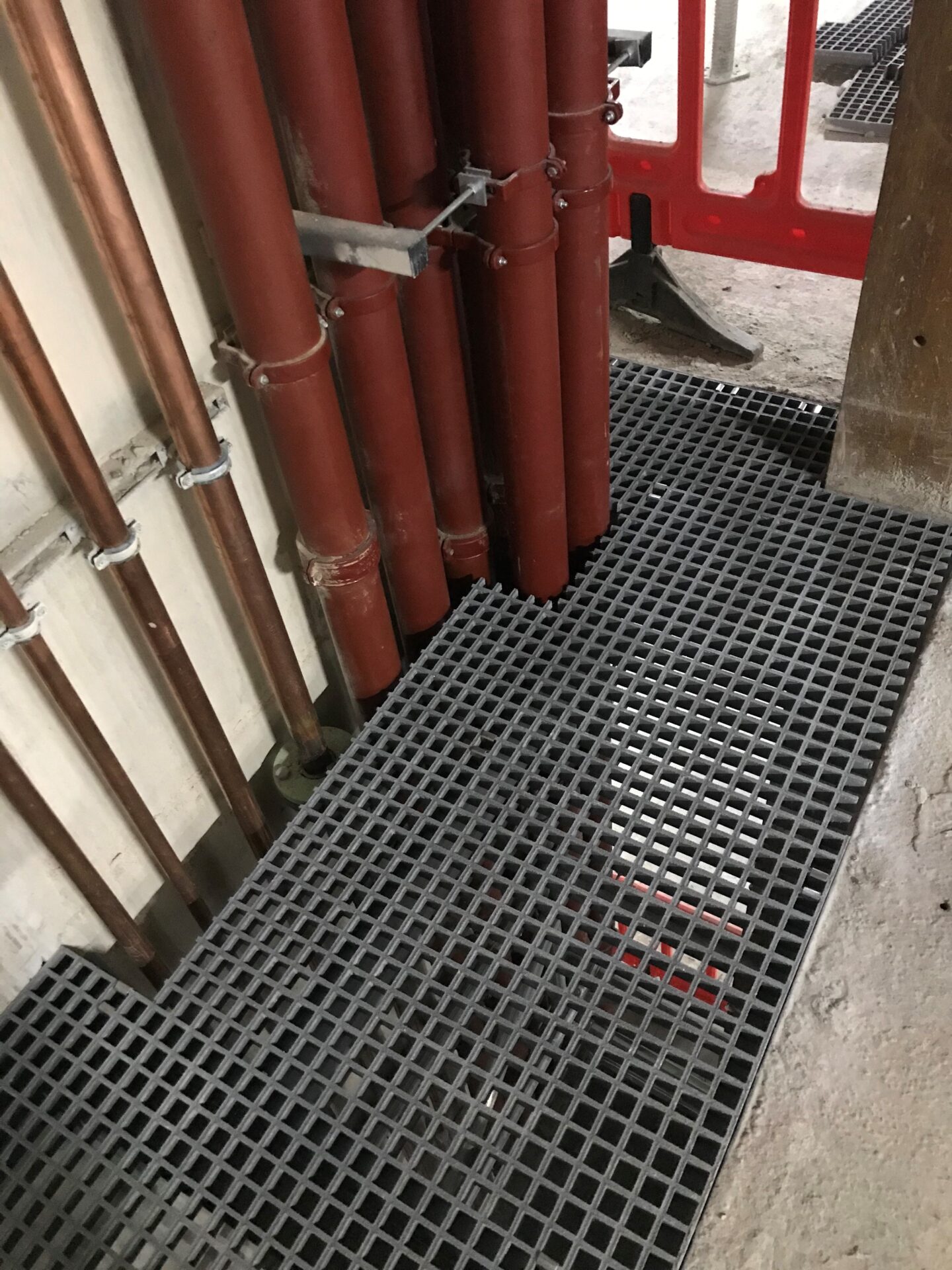 RiserDeck service riser floor with grey GRP grating cut around water &drainage pipes