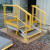 Access stairs with handrail at an open doorway at a grey kiosk