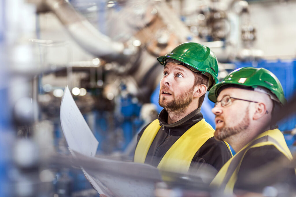 Two men in PPE doing a Risk Assessment in a factory
